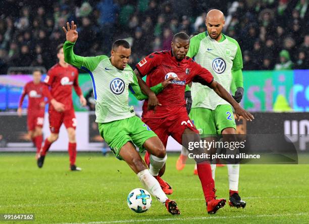 Marcel Tisserand and John Anthony Brooks of Wolfsburg and Freiburg's Karim Guede vie for the ball during the Bundesliga soccer match between VfL...