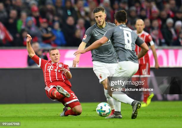 Bayern Muich's Joshua Kimmich in action with Augsburg's Jeffrey Gouweleeuw and Rani Khedira during the German Bundesliga football match between...