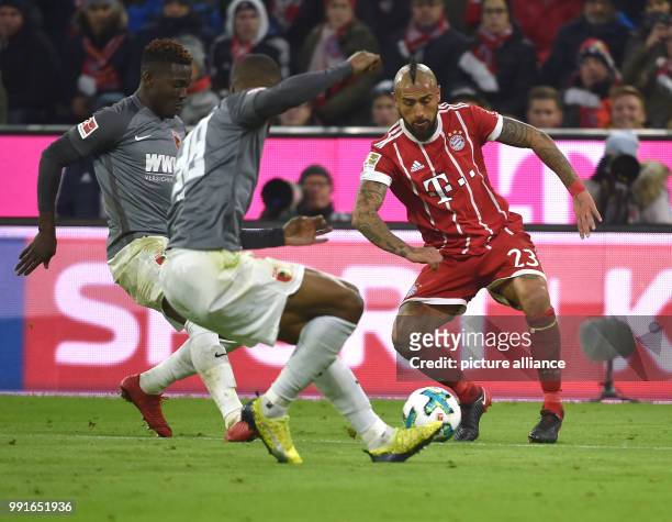 Munich's Arturo Vidal and Augsburg's Daniel Opare and Kevin Danso vie for the ball during the Bundesliga soccer match between Bayern Munich and FC...