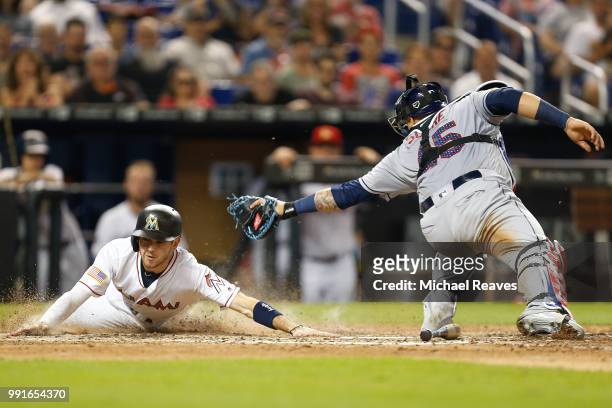 Riddle of the Miami Marlins slides home safely past the tag of Jesus Sucre of the Tampa Bay Rays in the sixth inning at Marlins Park on July 4, 2018...