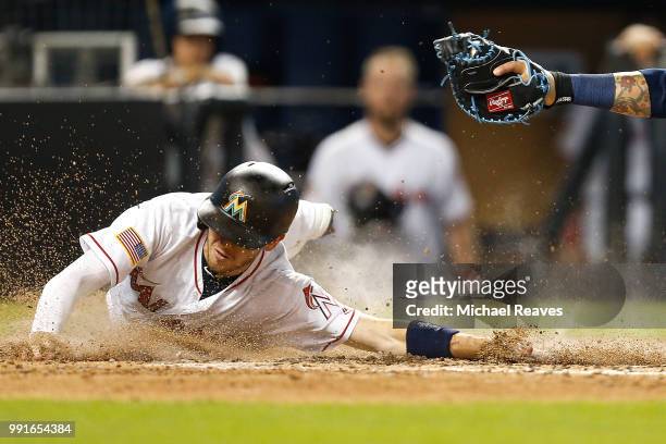 Riddle of the Miami Marlins slides home safely past the tag of Jesus Sucre of the Tampa Bay Rays in the sixth inning at Marlins Park on July 4, 2018...