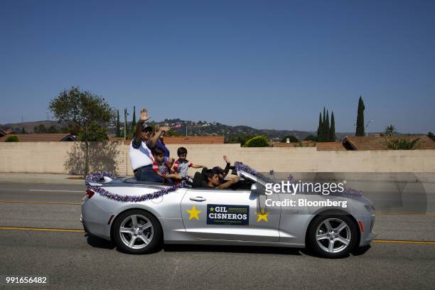 Gil Cisneros, Democratic U.S. Representative candidate from California, left, waves while riding in a car with his wife and sons during a Fourth of...