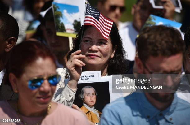 Citizenship candidates hold portraits of George Washington ahead of a naturalization ceremony at George Washington's Mount Vernon estate during...