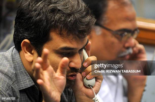 Pakistani stockbrokers talk on phones during a trading session at the Karachi Stock Exchange on May 13, 2010. The benchmark KSE 100-index was...