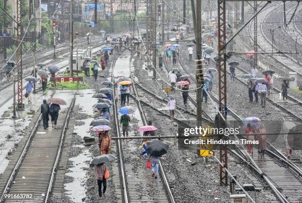 People walk on Railway track from Khar to Bandra on July 3, 2018 in Mumbai, India. Collapse of part of road overbridge near Andheri station led to...