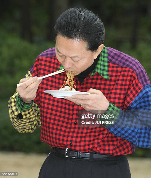 In a picture taken on April 4 Japanese Prime Minister Yukio Hatoyama eats noodles during a meet-the-people barbecue clad in a multi-coloured shirt at...