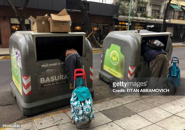 Men rummage through garbage bins in Buenos Aires, on June 26, 2018. - Market consultants in Argentina raised on July their inflation expectations for...