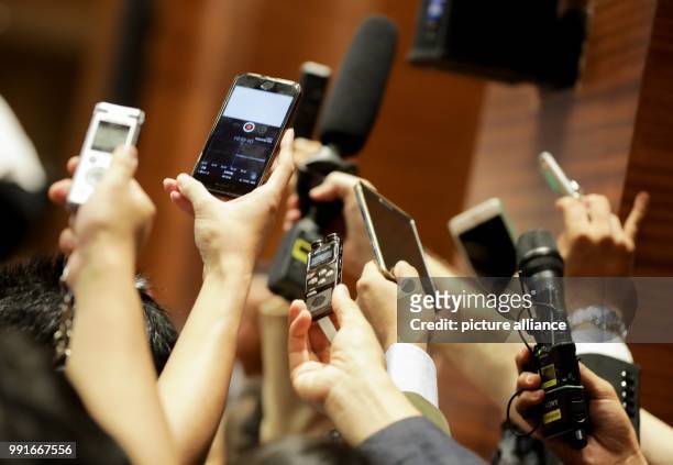 Participants hold their microphone to a loudspeaker to record the speech factual head of state and Foreign Minister Aung San Suu Kyi during the 13th...