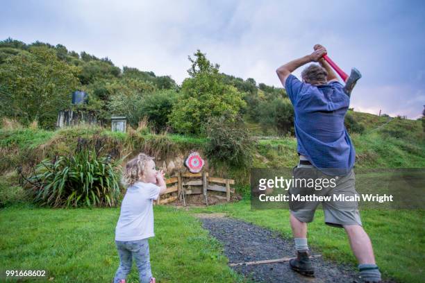 the blue duck lodge located in the whanganui national park is a working cattle farm with a focus on conservation. a man practices axe throwing as his daughter watches on. - axe throwing stock pictures, royalty-free photos & images