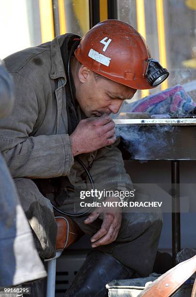 Russian miner smokes while resting near the Raspadskaya coal mine, in Mezhdurechensk on May 13, 2010 after making a rescue attempt. The death toll...