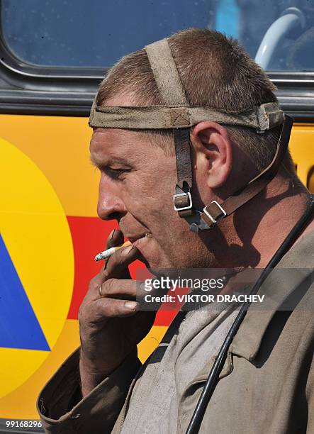 Russian miner smokes while resting near the Raspadskaya coal mine, in Mezhdurechensk on May 13, 2010 after making a rescue attempt. The death toll...