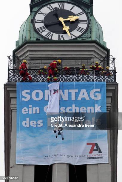 Woman ropes down from the tower of Saint Peter church in front of a banner reading 'Sunday - a gift from heaven' to demonstrate for work-free sundays...