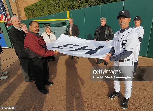 Members of Ernie Harwell's family along with first base coach Tom Brookens and Brandon Inge of the Detroit Tigers hold a flag in centerfield with...