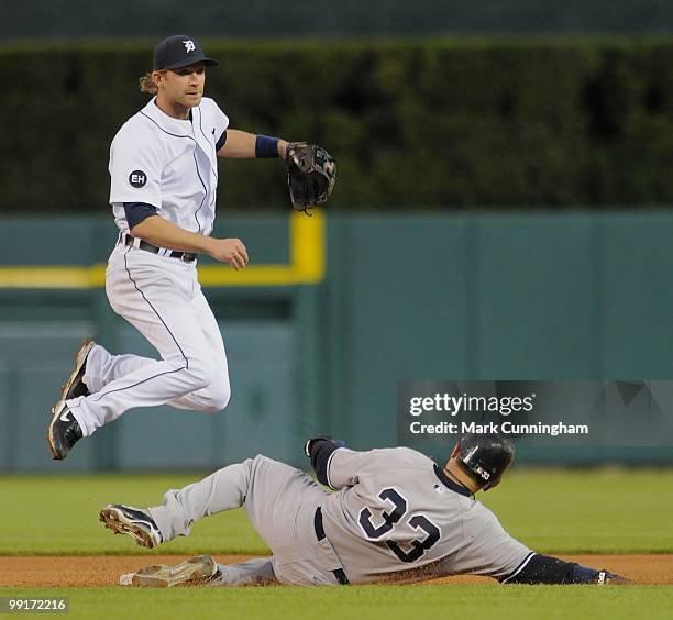 Nick Swisher of the New York Yankees is out at second base as Adam Everett of the Detroit Tigers leaps into the air to make the throw to first during...