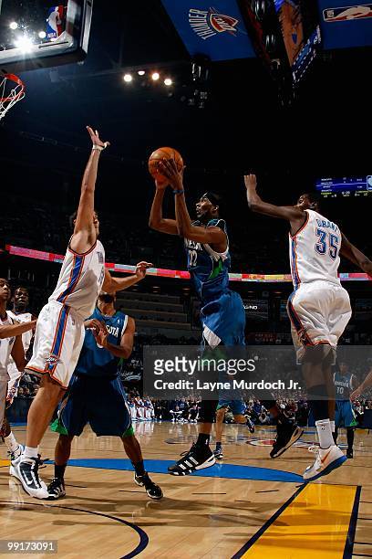 Corey Brewer of the Minnesota Timberwolves goes up for a shot against Nenad Krstic and Kevin Durant of the Oklahoma City Thunder during the game on...