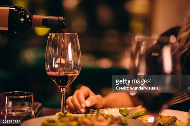 nahaufnahme des sommeliers servieren rotwein im fine-dining restaurant - eleganz stock-fotos und bilder
