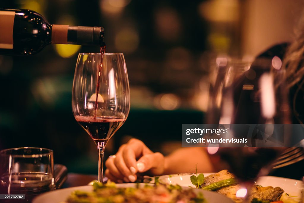 Primo piano di sommelier che serve vino rosso al raffinato ristorante