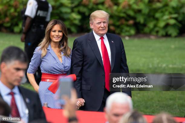 President Donald Trump and first lady Melania Trump walk on the South Lawn of the White House prior to greeting guests during a picnic for military...