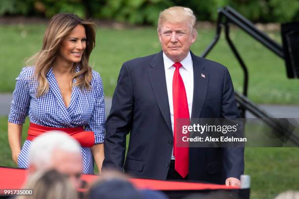 President Donald Trump and first lady Melania Trump walk on the South Lawn of the White House prior to greeting guests during a picnic for military...