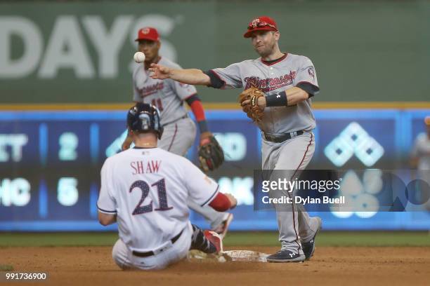 Brian Dozier of the Minnesota Twins turns a double play over Travis Shaw of the Milwaukee Brewers in the fourth inning at Miller Park on July 4, 2018...