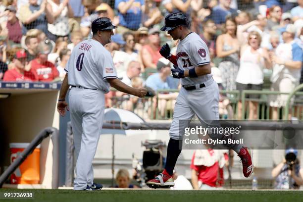 Third base coach Ed Seder and Travis Shaw of the Milwaukee Brewers celebrate Shaw's home run in the second inning against the Minnesota Twins at...