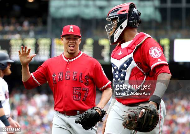 Hansel Robles of the Los Angeles Angels of Anaheim celebrates with Martin Maldonado after getting out of a bases-loaded jam in the seventh inning...