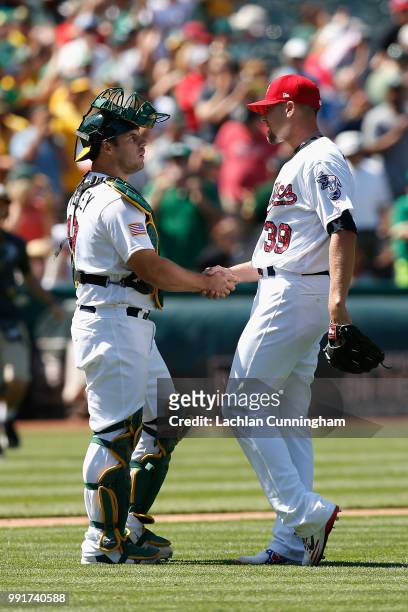 Josh Phegley and Blake Treinen of the Oakland Athletics celebrate after a win in their game against the San Diego Padres at Oakland Alameda Coliseum...