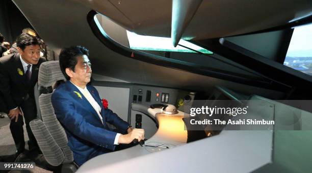 Japanese Prime Minister Shinzo Abe tries a Shinkansen E5 driving simulator after attending the opening ceremony of the renewed Railway Museum on July...