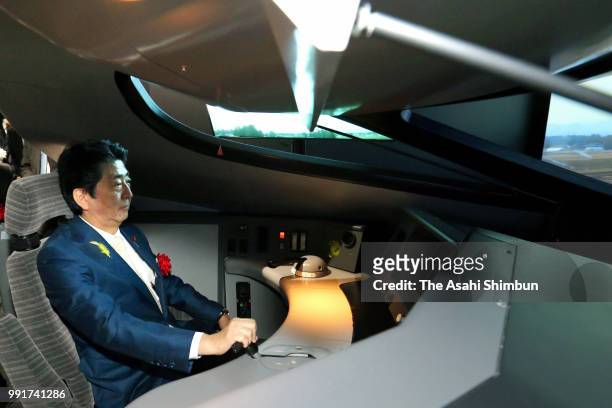 Japanese Prime Minister Shinzo Abe tries a Shinkansen E5 driving simulator after attending the opening ceremony of the renewed Railway Museum on July...