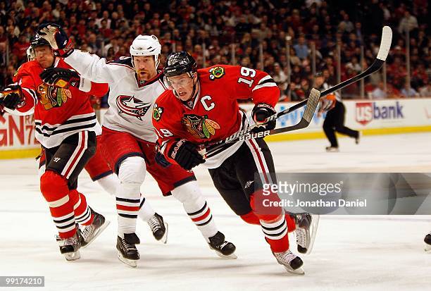 Jonathan Toews and Marian Hossa of the Chicago Blackhawks and Mike Commodore of the Columbus Blue Jackets battle for position as they chase down the...