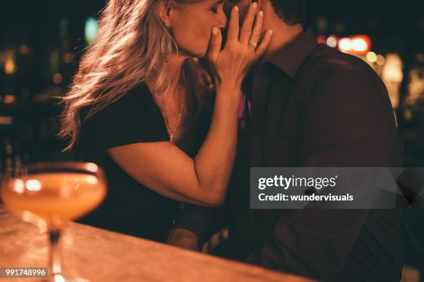 elegante pareja besos en cita romántica noche en el bar - besar fotografías e imágenes de stock