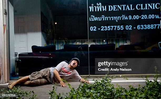 An anti-government protester yells as he takes cover as Thai security forces open fire on protesters on May 13, 2010 in Bangkok, Thailand. Protesters...