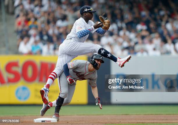 Didi Gregorius of the New York Yankees leaps over Ender Inciarte of the Atlanta Braves after a force out at second base during the first inning at...