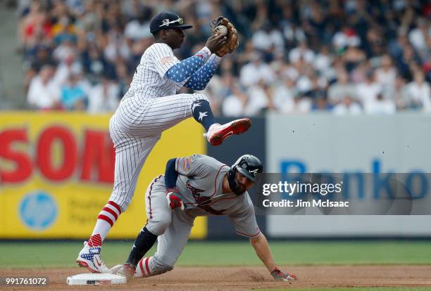 Didi Gregorius of the New York Yankees leaps over Ender Inciarte of the Atlanta Braves after a force out at second base during the first inning at...