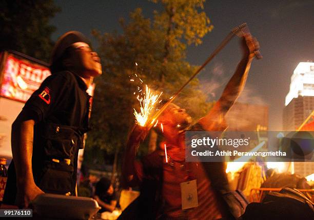 Anti-government 'Red Shirt' protesters use a sling shot to launch a fire cracker towards Thai security forces from inside their encampment on May 13,...