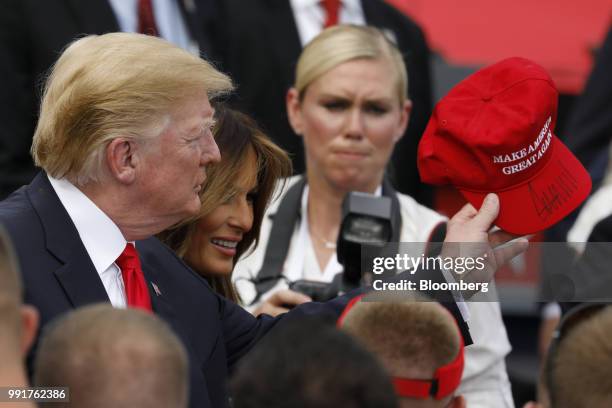 President Donald Trump, left, holds an autographed "Make America Great Again" hat as he greets guests with First Lady Melania Trump, second left, at...