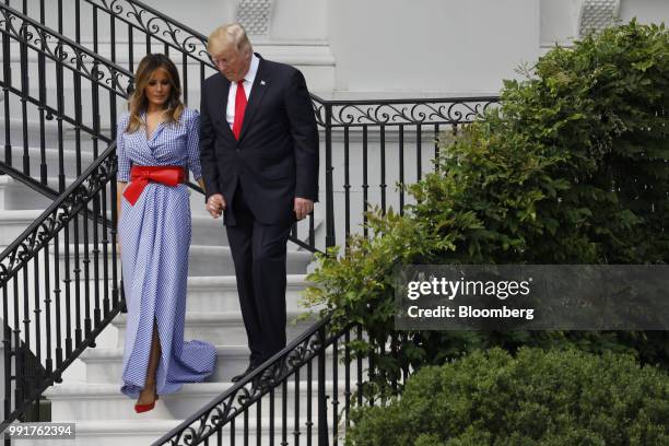 President Donald Trump, right, and First Lady Melania Trump walk down a flight of stairs as they arrive at a picnic for military families in...