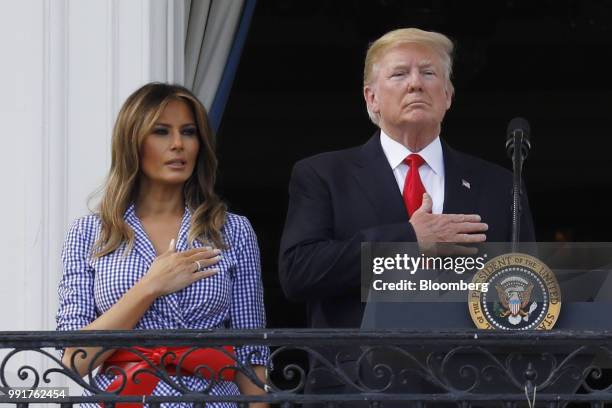 President Donald Trump, right, and First Lady Melania Trump place their hands over their hearts for the National Anthem at a picnic for military...