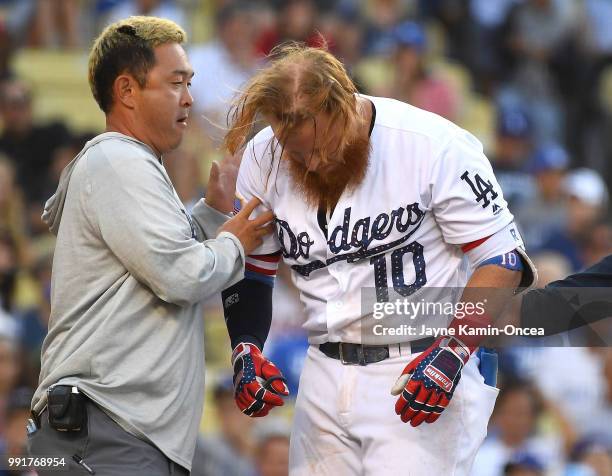 Justin Turner of the Los Angeles Dodgers is tended to by assistant athletic trainer Yosuke Nakajima after being hit in the head by a pitch from Tyler...