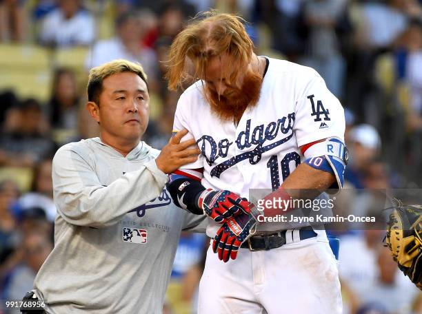 Justin Turner of the Los Angeles Dodgers is tended to by assistant athletic trainer Yosuke Nakajima after being hit in the head by a pitch from Tyler...