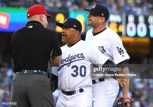 Manager Dave Roberts and relief pitcher Daniel Hudson of the Los Angeles Dodgers argue with first base umpire Jeff Nelson after Hudson was ejected...