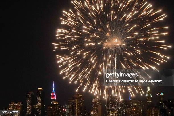 The Empire State Building is lit on blue, white and red as People watch the Macy's Fourth of July Fireworks from Hunter Point Park on July 4, 2018 in...