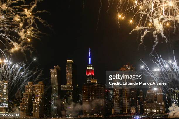 The Empire State Building is lit on blue, white and red as People watch the Macy's Fourth of July Fireworks from Hunter Point Park on July 4, 2018 in...