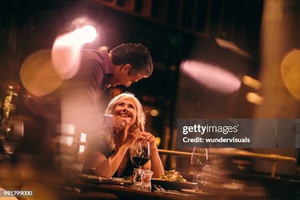middle-aged couple flirting on dinner date night at gourmet restaurant - old couple restaurant stock pictures, royalty-free photos & images
