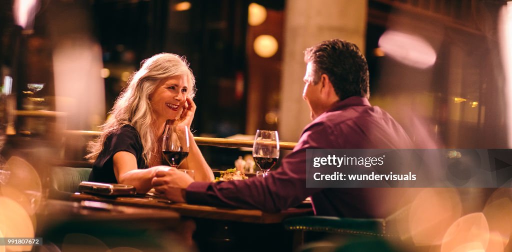 Loving senior couple holding hands on romantic dinner date night