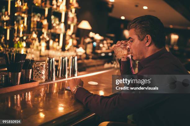 elegant mature man at bar drinking and checking the time - esperar alguém imagens e fotografias de stock