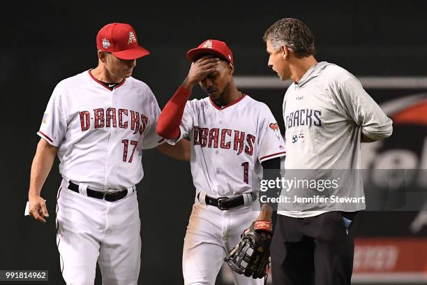 Jarrod Dyson of the Arizona Diamondbacks is walked off the field with manager Torey Lovullo and director, sports medicine and performance Ken...