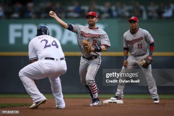 Brian Dozier of the Minnesota Twins attempts to turn a double play past Jesus Aguilar of the Milwaukee Brewers in the first inning at Miller Park on...