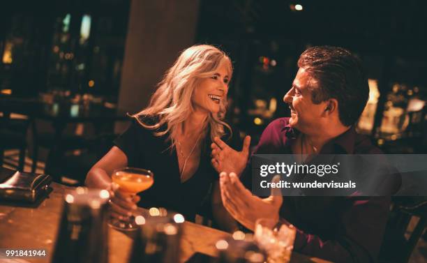 senior man en vrouw lachen en met drankjes in bar - flirten stockfoto's en -beelden