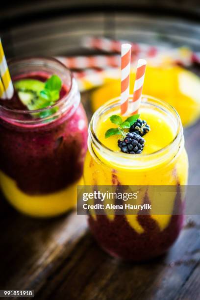 colorful two layer smoothies with mango and berries on rustic wo - mango leaf stock pictures, royalty-free photos & images